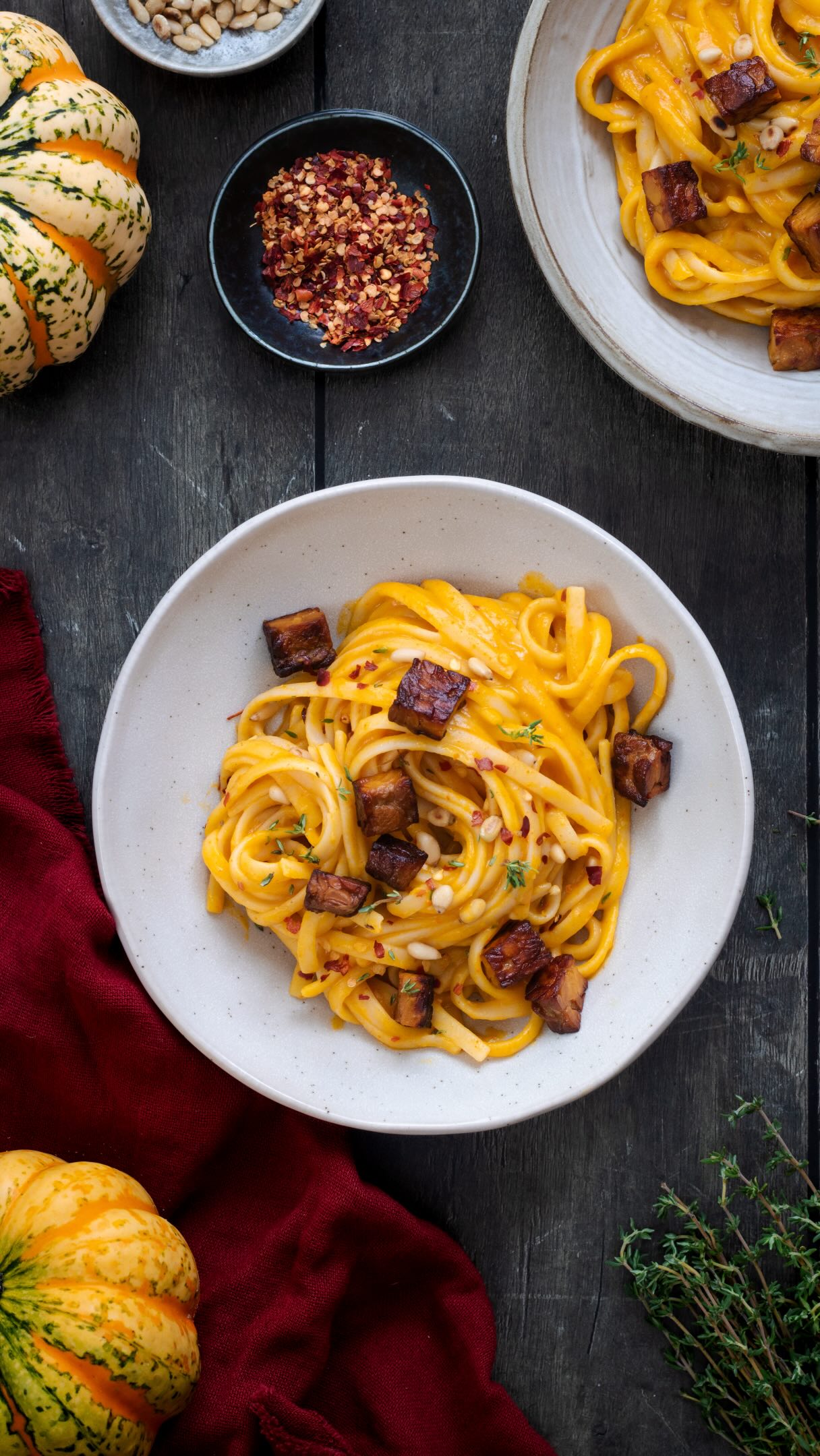 Byl by to snad dokonce hřích, obejít na podzim recept na těstoviny s dýňovou omáčkou a chilli 🤩🌶️ Obzvlášť, když v lednici máte nachystané hladké pyré. Máte? 😃 Připomínám, že recept najdete v nedávném reelsku.
Tohle jídlo máte hotové, když hodně v klidu, tak za 15 minut. A přitom nadělá tolik parády.🤩

Jinak k těstovinám jsem opekla na kostičky pokrájený lupinový tempeh, který pak nádherně křupe a krom živin dodá jídlu i báječnou chuť.

Ingredience na 2 porce:
Omáčka:
250 g dýňového pyré
1 stroužek česneku
2 lžičky rajského protlaku
1 rovná lžička tymiánu
špetka kajenského pepře
Čerstvě mletý pepř, ideálně kampotský
Sůl
50 ml smetany ke šlehání (může být i kokosová alternativa – husté kokosové mléko)
Doporučuji přidat i 2 lžíce nastrouhaného parmezánu, vegani mohou dát lžíci lahůdkového droždí

Dále potřebujete:
200 g špaget nebo jiných těstovin
Hrstka piniových semínek
Olej
Čerstvá šalvěj nebo tymián
Chilli vločky

Postup:
1) Dýňové pyré, česnek, protlak, tymián, kajenský pepř, větší špetku černého pepře, smetanu nebo kokosové mléko (a parmezán) rozmixujte dohladka.
2) Dejte vařit špagety do osolené vody. Před scezením odeberte z hrnce hrnek vody.
3) Piniová semínka nasucho opečte na pánvi.
4) Ve velké pánvi zahřejte dýňovou omáčku. Přidejte trochu vody z těstovin a chvíli míchejte.
5) Do pánve přidejte špagety a míchejte s omáčkou. Podle potřeby přilévejte vodu z těstovin. Když se těstoviny obalí krémovou omáčkou, rozdělte na talíře. Posypejte piniovými semínky, chilli vločkami a můžete případně ozdobit křupavými šalvějovými lístky.
Ty uděláte tak, že:
V čisté pánvi rozehřejte 2 lžíce oleje a šalvějové lístky na středním stupni opékejte dokřupava. Pozor, abyste je nespálili.
#dyne #testoviny #rychlerecepty #zdravejidlo #jidlo